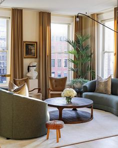 a living room filled with lots of furniture next to tall windows and curtains on the window sill