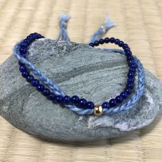 a blue beaded bracelet sitting on top of a rock