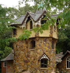 an unusual house made out of rocks in the woods