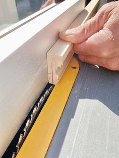 a person using a piece of wood to cut through a window