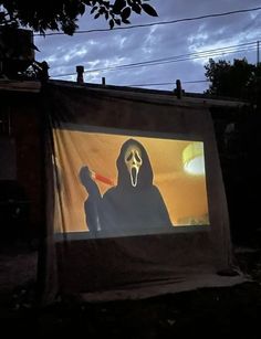 a movie screen with a person wearing a mask and holding a knife in front of it