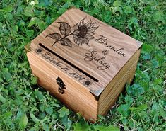 a wooden box sitting in the grass with a sunflower on it's lid