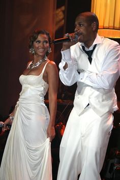 a man and woman dressed in white singing into microphones