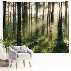 a chair sitting in front of a forest wall hanging on the side of a wall