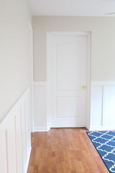 an empty room with hard wood flooring and white trim on the walls, along with a blue rug