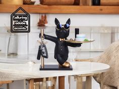 a black cat figurine holding a tray with keys on it's arm