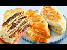 a hand holding up a stack of food on a blue and white plate next to some dumplings