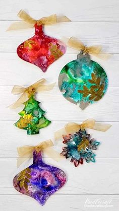 christmas ornaments made out of paper and ribbon hanging on a white wooden background with text overlay