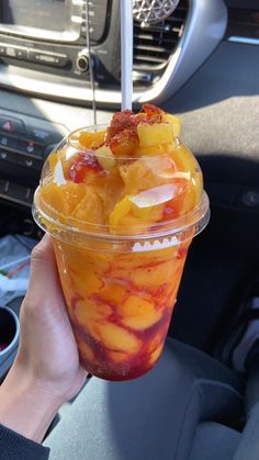 a person holding up a plastic cup filled with fruit