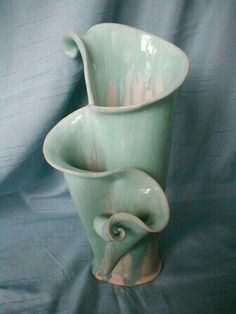 a large green vase sitting on top of a blue cloth