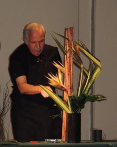 a man standing next to a tall bamboo plant