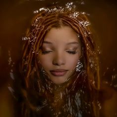 a woman with dreadlocks is in the water and looks down at her face