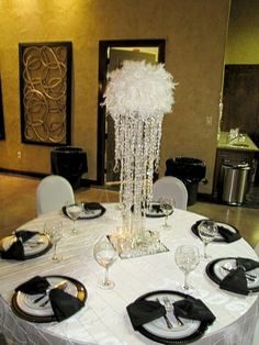 a table set with black and white plates, silver place settings and centerpieces