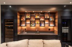 a living room filled with furniture next to a wine rack and bottles on the wall