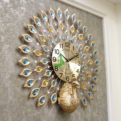 a clock that is on the wall with blue and gold feathers attached to it's face