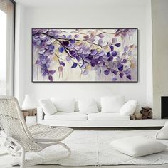 a living room with white furniture and purple flowers on the painting above the couches