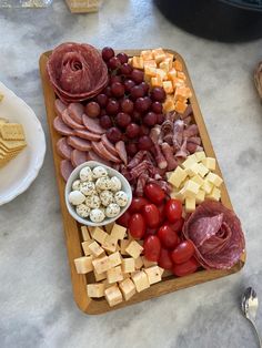 an assortment of cheeses, meats, and vegetables on a wooden platter