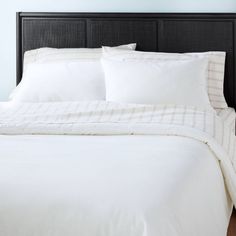 a bed with white sheets and pillows in a room