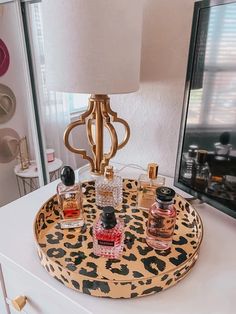 a leopard print tray with perfume bottles on it and a lamp in the corner next to it