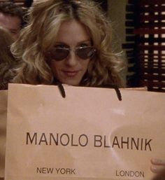 a woman holding up a sign that says manolo blohnikk new york