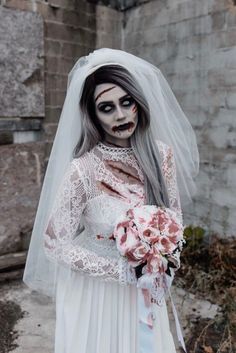 a woman in white wedding dress with makeup on her face and hands, holding a bouquet