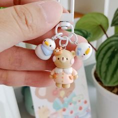 a hand holding a keychain with an animal charm on it