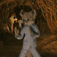 a man dressed as a fox standing in front of trees