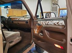 the interior of a vehicle with its door open and cow print seat covers on it