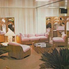 a living room filled with furniture next to a window covered in white curtains and palm trees