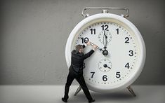 a man pushing a large white clock with the words time on it's face