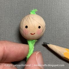 a person holding a pencil in their left hand and a small doll on the right