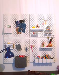 the wall is decorated with three pegboard boards and various items on it, including pens, scissors, pencils, markers, and other office supplies