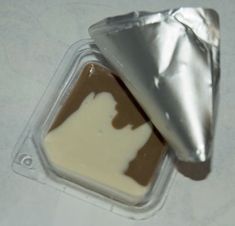 two pieces of chocolate with white icing in a plastic container on top of a table