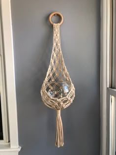 a macrame hanging from the wall with a wooden ring on it's end