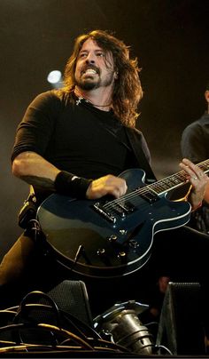 a man with long hair playing an electric guitar