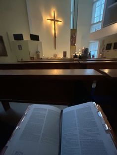 an open book sitting on top of a wooden table in front of a church pew