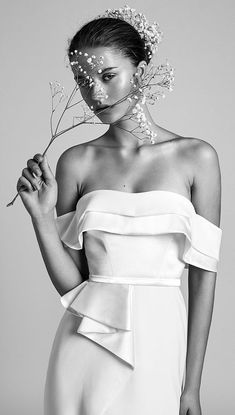 a woman in a white dress holding a flower