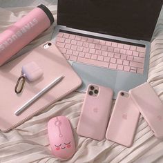 an open laptop computer sitting on top of a bed next to two pink iphone cases