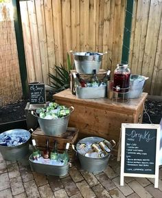 several buckets filled with drinks sitting on top of a wooden table next to a sign