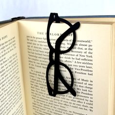 an open book with black glasses on it