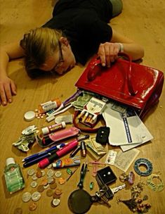 a woman laying on the floor with her purse full of money and other items around her