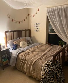 an unmade bed in a bedroom with curtains and lights on the wall above it