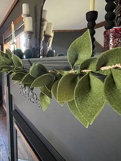 green leaves are hanging on the mantle in front of a mirror