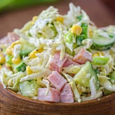 a wooden bowl filled with coleslaw salad on top of a table next to green peppers