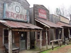 an old western town with wooden buildings and metal awnings on the front porch