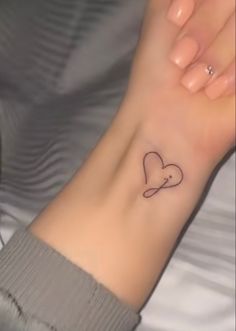 a woman's arm with a small heart tattoo on the left side of her wrist