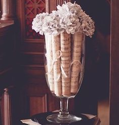 some wine corks are in a glass vase on a table with music sheets and flowers