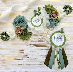 some paper flowers and ribbons on a wooden table with white ribbon around the edges that says daddy to be