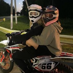 two people sitting on a motorbike with helmets on