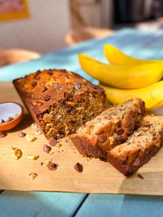 sliced banana bread sitting on top of a cutting board next to some bananas and nuts